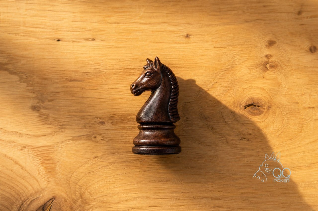 浅橡木桌面上一颗深色木质西洋棋马形棋子